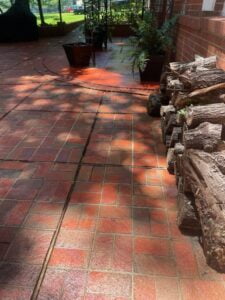 Image of a pressure clened patio. You can see a brick red brick patio that has been pressure cleaned.