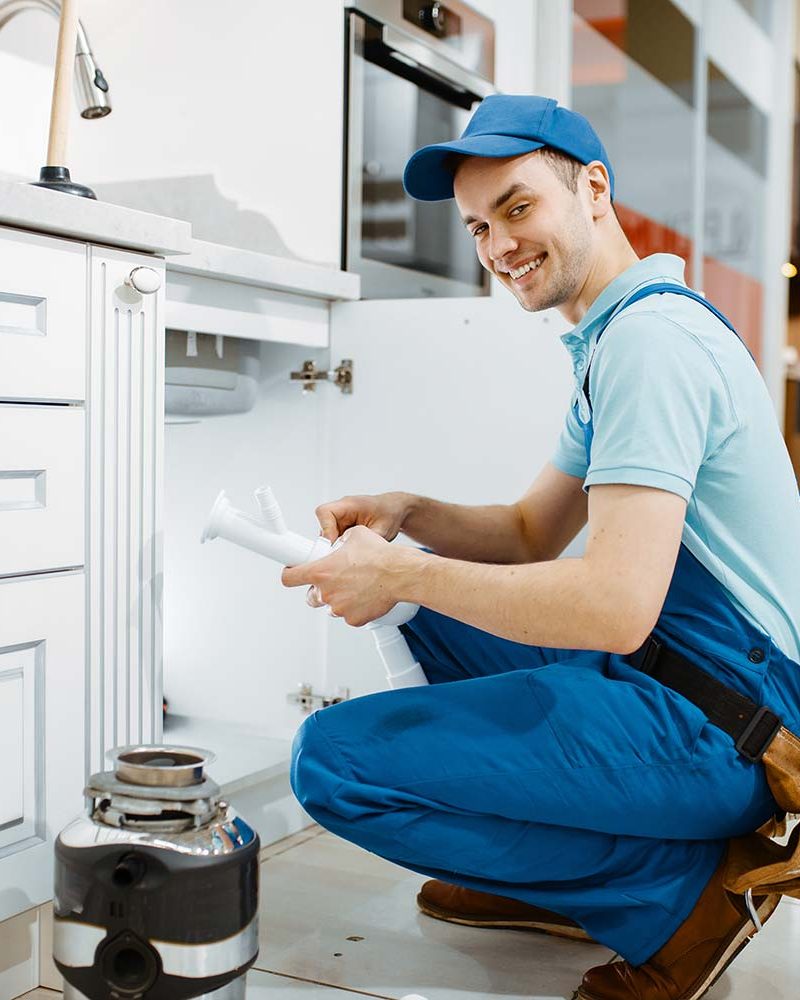smiling-male-plumber-in-uniform-holds-drain-pipe-resize.jpg